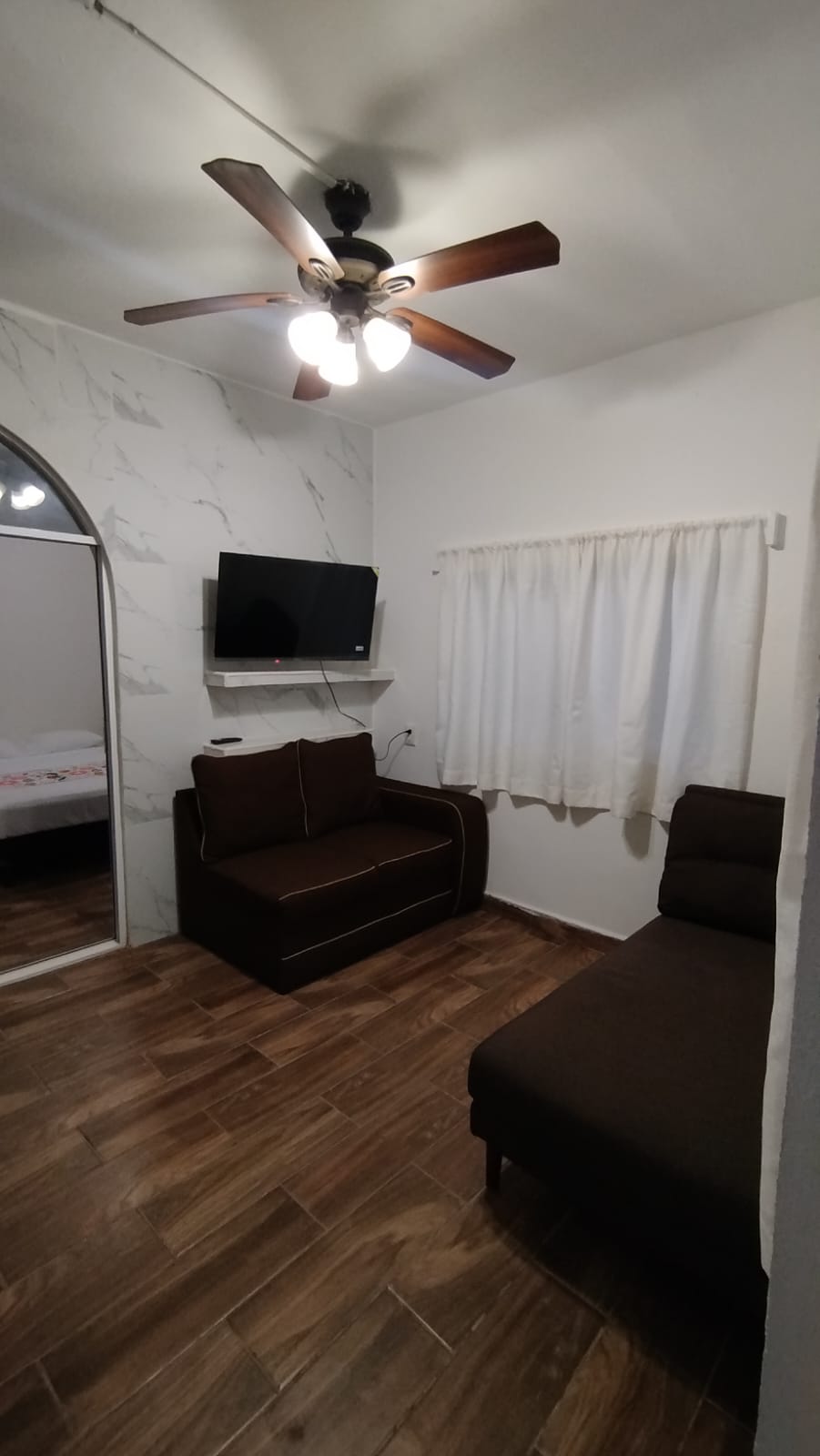 Vista de la sala, sillones, televisión y ventilador de techo.